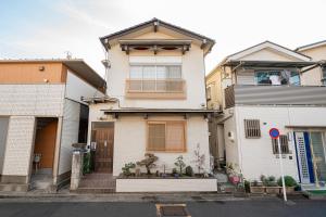 东京一戸建民泊 Tokyo St-ar House 東京星宿的一间白色的房子,有棕色的门和一些建筑