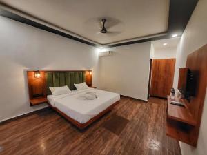 阿姆波尔Rashiva Resort的卧室配有一张白色的大床,铺有木地板