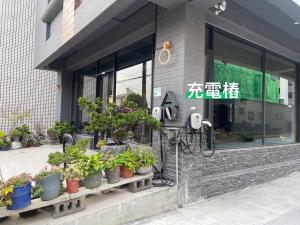 Chaozhou屏東潮州民宿-綠品文旅Green Inn的一座种植盆栽植物的建筑前的付费电话