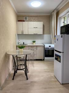 乌斯季卡缅诺戈尔斯克Аппартаменты 2 / х комнатная的厨房配有桌子和白色冰箱。