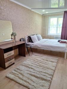 乌斯季卡缅诺戈尔斯克Аппартаменты 2 / х комнатная的一间卧室配有一张床、一张桌子和一张地毯。