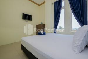 PaciranGrand Kencana Guesthouse near Wisata Bahari Lamongan Mitra RedDoorz的一间卧室配有一张带蓝色窗帘的床和电视。