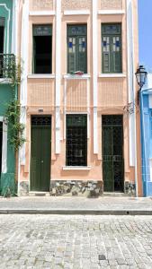 萨尔瓦多Hostel Canto Zen的一条粉红色的建筑,在街上设有绿门