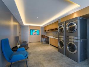 禹城丽柏酒店山东禹城高新区德百广场的洗衣房配有3台洗衣机和烘干机