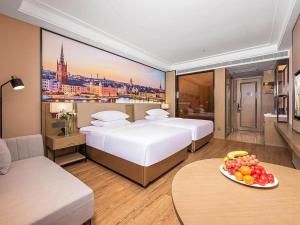 咸阳维也纳国际西安咸阳国际机场酒店的酒店客房设有两张床和一张带果盘的桌子。