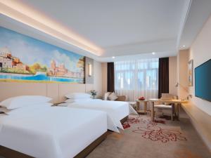 莆田维也纳国际福建莆田明珠酒店的酒店客房设有两张床,墙上挂有绘画作品