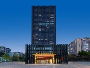 重庆维也纳国际重庆江北嘴金融中心酒店的一座高大的黑色建筑,前面有一个门