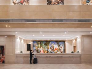 莆田维也纳国际福建莆田明珠酒店的带着手提箱的人,看着博物馆里的一幅画
