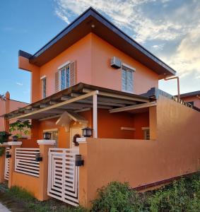 武端市Brand New Camella 2 Bedroom House的一座橙色房子,前面有栅栏