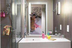 卡萨诺韦米兰马尔彭萨机场慕奇夕酒店的浴室设有水槽,镜子里有一个女人