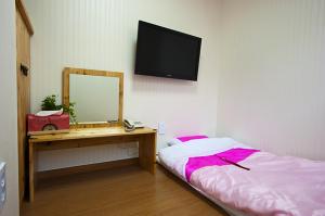 首尔明洞环保旅馆的一间卧室配有书桌、镜子和床