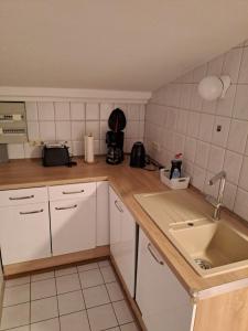 HohenwestedtFerienwohnung Schulze的厨房配有白色橱柜和水槽