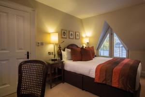 埃文河畔斯特拉特福Ettington Park Hotel, Stratford-upon-Avon的一间卧室设有一张床、一个窗口和一把椅子