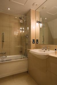 埃文河畔斯特拉特福Ettington Park Hotel, Stratford-upon-Avon的浴室配有水槽、淋浴和浴缸。