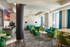 泰恩河畔纽卡斯尔Leonardo Hotel Newcastle的一间设有绿色椅子和桌子的等候室