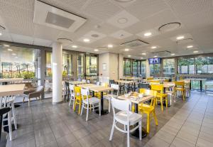 朗贡B&B HOTEL Bordeaux Langon的用餐室配有桌子和黄色椅子