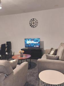 阿克灵顿4-Bed House in Accrington的带沙发、电视和时钟的客厅