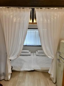庆州Hanok Dasi Bom 101的窗户客房内的一张带白色窗帘的床
