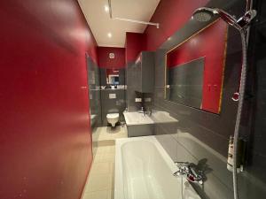 柏林霍宁格莫地精品酒店的一间带红色墙壁、浴缸和水槽的浴室