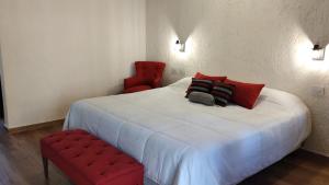 查克拉斯德科里亚朝圣者小憩酒店的卧室配有白色的床和红色椅子