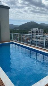 乌巴图巴Lindo apartamento Ubatuba的一座大型蓝色游泳池,位于一座建筑的顶部