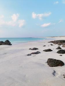 Al QārinMasirah Beach camp的沙滩上,沙滩上,海洋上,岩石上