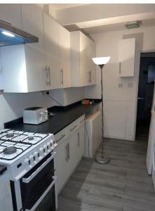 伦敦COZY ROOMS 25 min LIVERPOOL STREET的厨房配有炉灶、白色橱柜和灯具