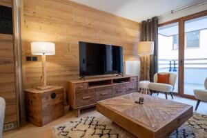 于埃Charming three-room apartment in Huez - Welkeys的客厅设有木墙,配有平面电视。