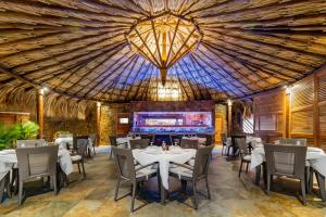 El YaqueVientos del Caribe Club & Hotel的一间带桌椅和大型天花板的餐厅