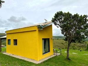 圣若昂-巴蒂斯塔-杜格罗里亚Canastra - Chalés Canário de Minas的一片绿地中的黄色房子