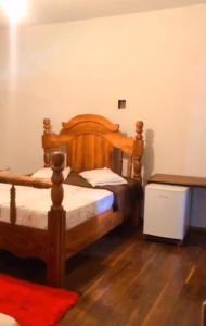 Rio NovoHOTEL FAZENDA CANARIO DA TERRA的一间卧室设有一张木床,铺有木地板。