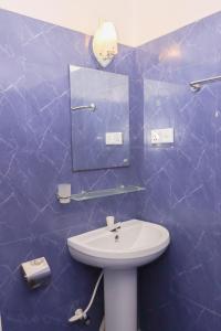 阿鲁甘湾Chimaca Bay Hotel的蓝色瓷砖浴室设有水槽和镜子
