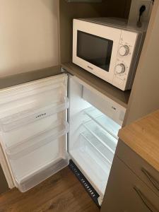 拉尔莫普拉格Cosy's Terrasse的厨房配有微波炉和空冰箱。