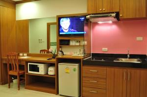 芭东海滩绿色海港酒店 & 服务公寓的一个带水槽的厨房和墙上的电视