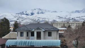 卡拉科尔Karakol Yurt Lodge & Homestay的雪覆盖的山前的房子