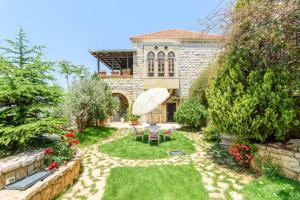 Authentic Villa with Pool and Garden in Beit Chabeb的一座带椅子和遮阳伞的花园的房子