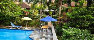 阿比让阿比让绿洲别墅旅馆的一个带蓝伞和桌椅的游泳池