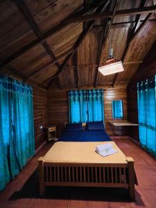 玛纳多迪Royal Wooden villa的一间卧室配有一张带蓝色窗帘的大床