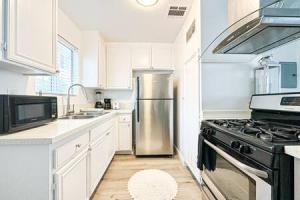 洛杉矶Dual-Level Delight 2BR in Hollywood - BR4-BH的厨房配有不锈钢冰箱和白色橱柜