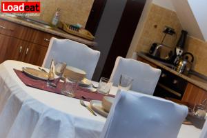 扎马迪NORA Guesthouse and Restaurant的一张桌子,上面摆放着白色的椅子和盘子,玻璃杯