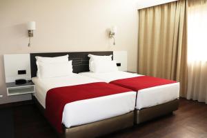马托西纽什Hotel Amadeos - Matosinhos - Porto的一间卧室配有一张带白色和红色床单的大床