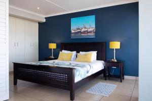 StompneusbaaiZeezicht Apartments的一间卧室拥有蓝色的墙壁,配有一张带黄色枕头的床。