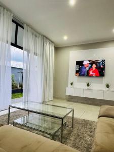 LobambaEkhaya Luxury Apartment的客厅配有玻璃桌和电视