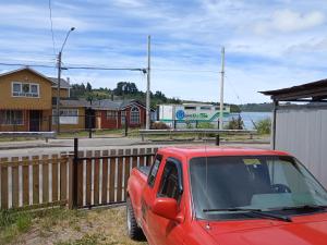 卡斯特鲁Hostal Sandrita的停在木栅栏旁边的一辆红色卡车