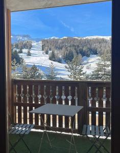 德沃吕伊Superdévoluy, appartement récent - en face et au pied des pistes的阳台的桌子,享有白雪 ⁇ 的山景