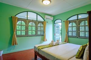 蔻立Bann Mangkud Khaolak的一间拥有绿色墙壁的卧室和一张窗户床