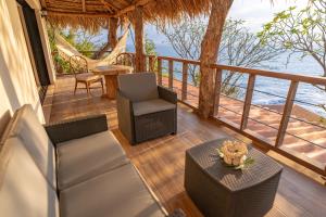 El NísperoParaiso Escondido Hotel Villas & Resort的一个带椅子和桌子的门廊,享有海景