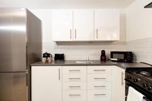 奥尔德姆Suite 6 - Double Room in the Heart of Oldham的厨房配有白色橱柜和不锈钢冰箱