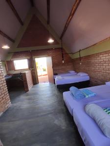 圣罗克迪米纳斯Pousada do Chicó的带三张床和砖墙的房间
