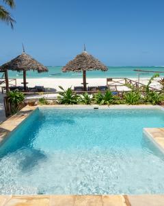 普瓦尼梅查恩加尼Villa Thamani Zanzibar的海滩旁的游泳池,配有遮阳伞